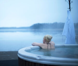 Kvinna sitter i bubbelbad och tittar ut över sjön Skedviken